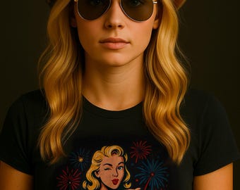 May include: A woman wearing a cowboy hat with a stars and stripes design, aviator sunglasses, and a black t-shirt. The t-shirt features a retro illustration of a woman winking and the text "Talk American to Me."