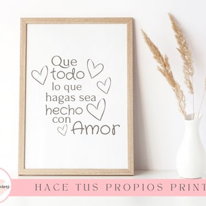 Peut inclure: Impression encadrée avec l'inscription "Que todo lo que hagas sea hecho con Amor" en noir, entourée de cœurs. Le cadre est marron clair. Un vase blanc avec des fleurs séchées est à droite.