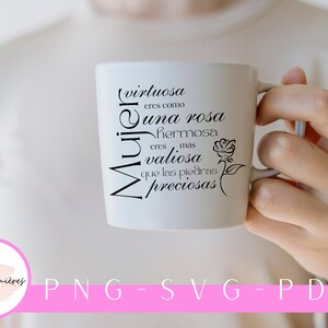 Op de afbeelding: Een witte keramische mok met zwarte tekst die "(virtuosa eres como una rosa hermosa eres mas valiosa que las piedras preciosas)" luidt en een zwart silhouet van een roos. De mok wordt vastgehouden door een hand.