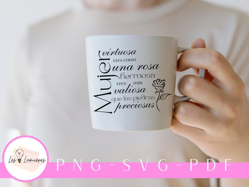Op de afbeelding: Een witte keramische mok met zwarte tekst die "(virtuosa eres como una rosa hermosa eres mas valiosa que las piedras preciosas)" luidt en een zwart silhouet van een roos. De mok wordt vastgehouden door een hand.