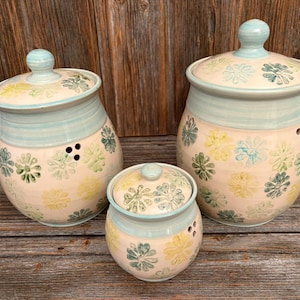 Op de afbeelding: Een witte keramische mok met een zwart handvat en de tekst "But First, Coffee" in een zwarte, vette letter. De mok staat op een wit oppervlak.