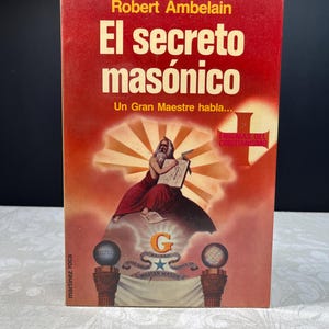 May include: A book cover with the title "El secreto masónico" in large, yellow letters on a red background. The cover features an illustration of a robed figure holding a tablet, with Masonic symbols.