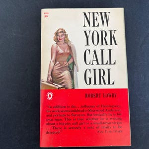 以下が含まれることがあります： ロバート・ローリー著のヴィンテージペーパーバック『New York Call Girl』。表紙には、金色のドレスを着てスーツケースを持つ金髪の女性のイラストが描かれています。背景は白で、黒い文字と下部に赤いセクションがあります。