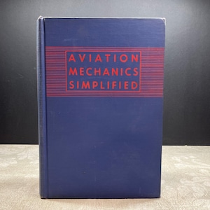 May include: Aviation Mechanics Simplified book. The book has a navy blue cover with the title in red block letters. The title is set within a red rectangular border. The book is standing upright.