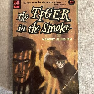 Puede incluir: Portada de libro de bolsillo vintage de "The Tiger in the Smoke" de Margery Allingham. La portada presenta una ilustración oscura de un rostro y figuras en un ambiente de humo. El título se muestra de forma destacada, con el logotipo de Dell Book.