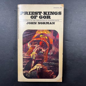 May include: A vintage paperback book titled Priest-Kings of Gor by John Norman, Volume III in the Chronicles of Counter-Earth. The cover features a colorful illustration of a figure in a loincloth standing over a reclining person in a cavern.