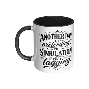 Puede incluir: Taza de cerámica blanca con interior, asa y borde negros. La taza presenta el texto "Another Day of Pretending the Simulation Isn't Lagging" en escritura negra.