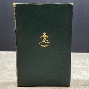 May include: A dark green book with gold lettering and a logo. The book has a textured cover and the words "Modern Library" are visible. The book is standing upright.