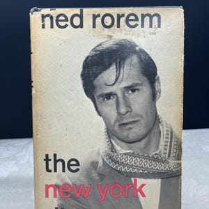 Könnte beinhalten: Vintage Buchcover für "The New York Diary" von Ned Rorem. Das Cover zeigt ein Schwarz-Weiß-Porträt eines Mannes mit einem gemusterten Schal. Der Titel ist in Schwarz und Rot gehalten, mit dem Namen des Autors oben.