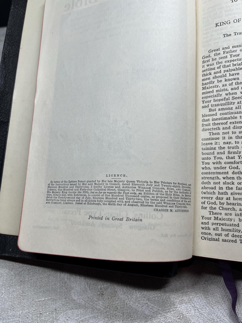 Puede incluir: Biblia abierta con texto visible en las p&aacute;ginas, incluyendo la palabra "Licence" y "Printed in Great Britain". El libro tiene una cubierta negra y bordes de p&aacute;gina rojos. Las p&aacute;ginas son de color blanquecino.