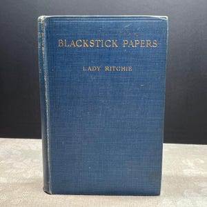 Pode incluir: Um livro antigo de capa dura azul intitulado "Blackstick Papers" de Lady Ritchie. O título e o nome da autora estão em letras douradas. A lombada mostra desgaste, sugerindo que é um item usado.