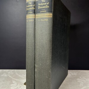 Puede incluir: Dos libros de tapa dura verde oscuro titulados "The Sculpture of Donatello" por Janson. Letras y detalles dorados en el lomo. La palabra "Princeton" está impresa en la parte inferior de cada libro.