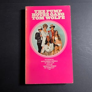 May include: A paperback book titled The Pump House Gang by Tom Wolfe with a bright pink cover. The center features a circular photograph of six people in various outfits. The bottom text reads: The definitive, super-charged chronicle of today's life.