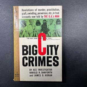 May include: A vintage paperback book titled Big City Crimes by Harold R. Danforth and James D. Horan. The white cover features a green-tinted illustration of six figures, bold black text, and a large red letter C. It includes the subtitle Revelations of murder, prostitution, graft, swindling, perversion, etc., in true accounts now told by The D.A.'s Man.