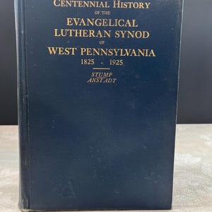 May include: A dark blue hardcover book with gold lettering. The title reads "Centennial History of the Evangelical Lutheran Synod of West Pennsylvania 1825-1925." The author's name, Stump Anstadt, is at the bottom.