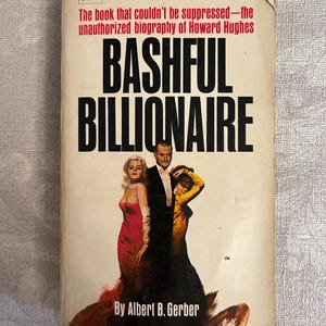 May include: Vintage paperback book titled "Bashful Billionaire" by Albert B. Gerber. The cover features a photo of three people and the text "The book that couldn't be suppressed - the unauthorized biography of Howard Hughes."