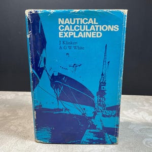 May include: A hardcover book titled Nautical Calculations Explained by J Klinkert and G W White. The cover is bright blue with dark blue illustrations of a large ship and a crane. The edges of the book cover show signs of wear and fraying.