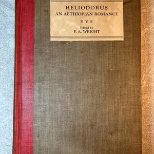 Puede incluir: Un libro de tapa dura titulado "HELIODORUS AN AETHIOPIAN ROMANCE", editado por F. A. Wright. El libro tiene una cubierta marrón con un lomo rojo. El título está impreso en una etiqueta rectangular.