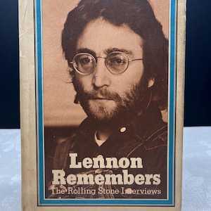 Könnte beinhalten: Ein Vintage-Buch mit dem Titel "Lennon Remembers" mit einem Porträt von John Lennon auf dem Cover. Das Cover hat einen braunen Hintergrund mit blauem Rahmen und Text. Das Buch enthält Interviews von The Rolling Stone.
