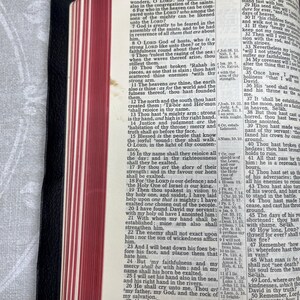 Puede incluir: Biblia abierta con bordes de p&aacute;gina rojos, que muestra el texto de Salmos 89. El libro est&aacute; encuadernado en cuero negro y est&aacute; abierto, revelando el texto y el lomo. Los bordes de las p&aacute;ginas son rojos.