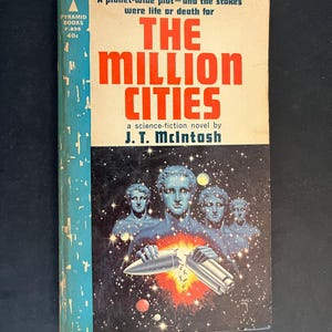 Könnte beinhalten: Ein Vintage-Taschenbuch mit dem Titel The Million Cities von J. T. McIntosh. Das Cover zeigt einen cremefarbenen oberen Bereich mit rotem Text, einen blauen Buchrücken und einen schwarzen unteren Teil mit vier blauen Statuen vor einem Sternenhimmel.