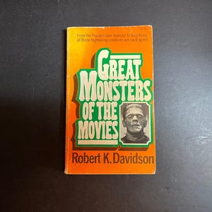 以下が含まれることがあります： ロバート・K・デヴィッドソン著のペーパーバック『Great Monsters of the Movies』。オレンジ色の表紙には緑色の文字と、フランケンシュタインの怪物の白黒ポートレートが描かれています。上部のテキストには「From the Frankenstein monster to King Kong」と記されています。