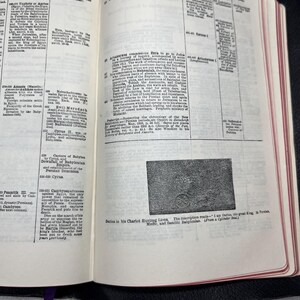 Puede incluir: Libro abierto con texto y una ilustraci&oacute;n. Las p&aacute;ginas son de color crema con texto negro y una peque&ntilde;a imagen de una escena de carro. El libro est&aacute; encuadernado en cuero negro con una cinta morada como marcador.