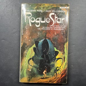 May include: A vintage paperback science fiction book titled Rogue Star by Frederik Pohl and Jack Williamson. The cover features a large, dark blue, organic-shaped structure set against a swirling orange and green nebula background with a small figure.