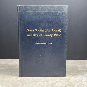 May include: A vintage book titled "Nova Scotia (S.E. Coast) and Bay of Fundy Pilot" in dark blue with gold lettering. The book is a fourth edition from 1966. The book is standing upright.