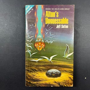 May include: A vintage Ace Double science fiction paperback book titled Alton's Unguessable by Jeff Sutton. The cover features a dark landscape with a glowing orange structure, white birds in flight, and a dark, textured orb resting in yellow grass.