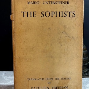Puede incluir: Un libro de color beige con el título "The Sophists" de Mario Untersteiner. El libro está traducido del italiano por Kathleen Freeman.