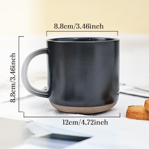 May include: A black ceramic mug with a brown base and a gray handle. The mug is 3.46 inches tall and 4.72 inches wide. The mug is 3.46 inches in diameter. The mug is on a white surface.