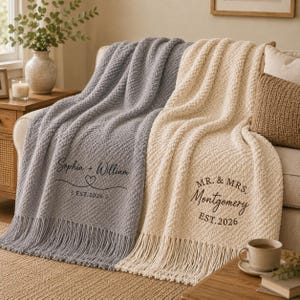 May include: Two textured knit throw blankets with fringe, one grey and one cream. The grey blanket features the text Sophia + William with a heart and EST. 2026. The cream blanket features the text MR. & MRS. Montgomery EST. 2026 in dark brown.