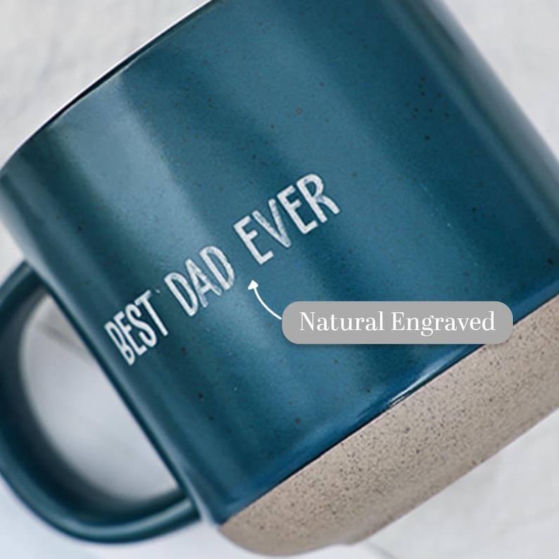 May include: A teal ceramic mug with the words "BEST DAD EVER" in white lettering. The bottom of the mug is a natural, unglazed color. The text "Natural Engraved" is also visible.