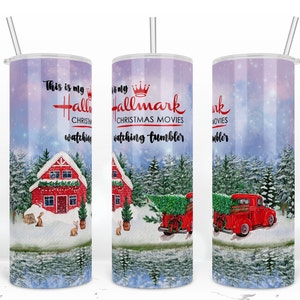 May include: A white tumbler with a winter scene and the text "This is my Hallmark Christmas Movies watching tumbler". The scene includes a red cabin, a red truck with a Christmas tree, and snow-covered trees.