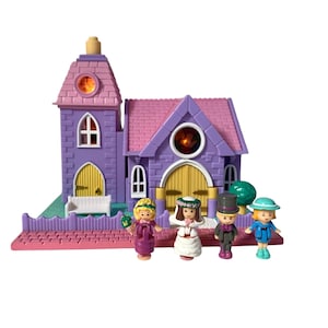 Op de afbeelding: Een vintage speelset met een paarse en roze kerk met een toren en gewelfde deuren. Vier miniatuurfiguren zijn gekleed in trouwkleding. Het speelgoed heeft een roze basis en een groene omheining.