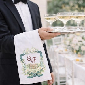 Waiter holding champagne tray with white towel featuring personalized watercolor wedding crest monogram at wedding reception.