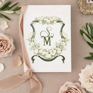 Wedding stationery featuring a personalized watercolor wedding crest monogram surrounded by ribbon, flowers and petals.