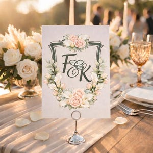 Wedding table card with a personalized watercolor wedding crest monogram displayed on an elegant reception table at sunset.
