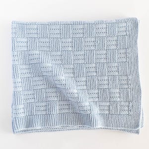 May include: A light blue knitted blanket with a woven basket weave pattern. The blanket is square and has a textured appearance. The soft, cozy blanket is perfect for a baby or child.