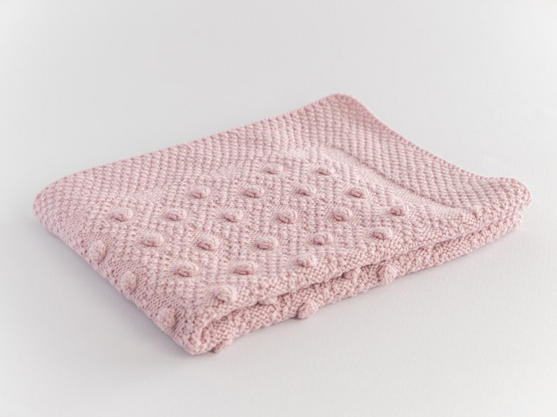 Pu&ograve; includere: Una coperta di maglia rosa chiaro piegata, con una superficie strutturata e un motivo a pois in rilievo. La coperta &egrave; realizzata in materiale morbido ed &egrave; adatta a un bambino. La coperta misura circa 76 cm di lunghezza e 64 cm di larghezza.