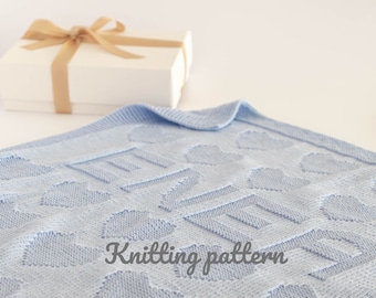 May include: A light blue knitted baby blanket with a heart pattern. The blanket is folded and has the words "Knitting pattern" written on it.