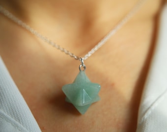 May include: A silver chain necklace with a green star-shaped pendant.