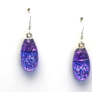 Peut inclure: Une paire de boucles d'oreilles pendantes en argent avec des gouttes en verre iridescentes de couleur violette.