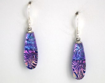May include: A pair of silver dangle earrings with iridescent purple and blue glass teardrop shaped drops.