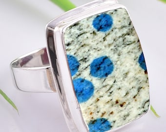 May include: A silver ring with a rectangular blue and white stone. The stone has a speckled pattern with blue spots.