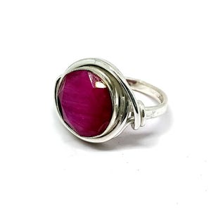 Peut inclure: Une bague en argent avec une pierre précieuse rose enveloppée de fil d'argent.