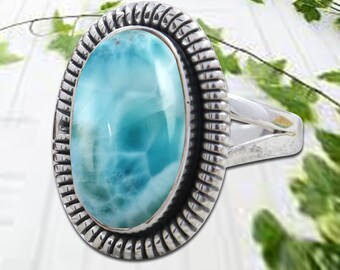 May include: A silver ring with a large oval-shaped blue and white gemstone set in a silver bezel. The ring has a textured band.