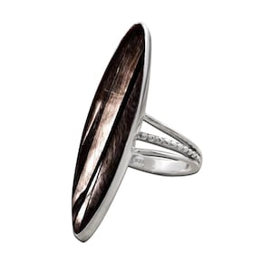 May include: A silver ring with a large, elongated oval stone. The stone has a dark brown and white striped pattern. The ring band splits into two sections, with a row of small beads on one section.