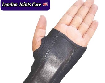 Pode incluir: Suporte de pulso preto com o texto "London Joints Care". O suporte é projetado para cobrir o pulso e parte da mão, com uma abertura para o polegar. O material parece ser uma combinação de tecido e um material liso e brilhante.